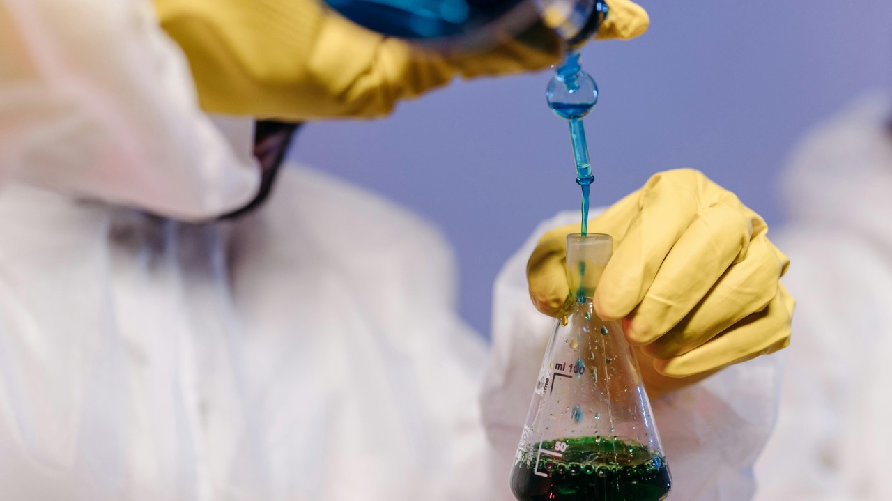 gloved hands mixing chemicals