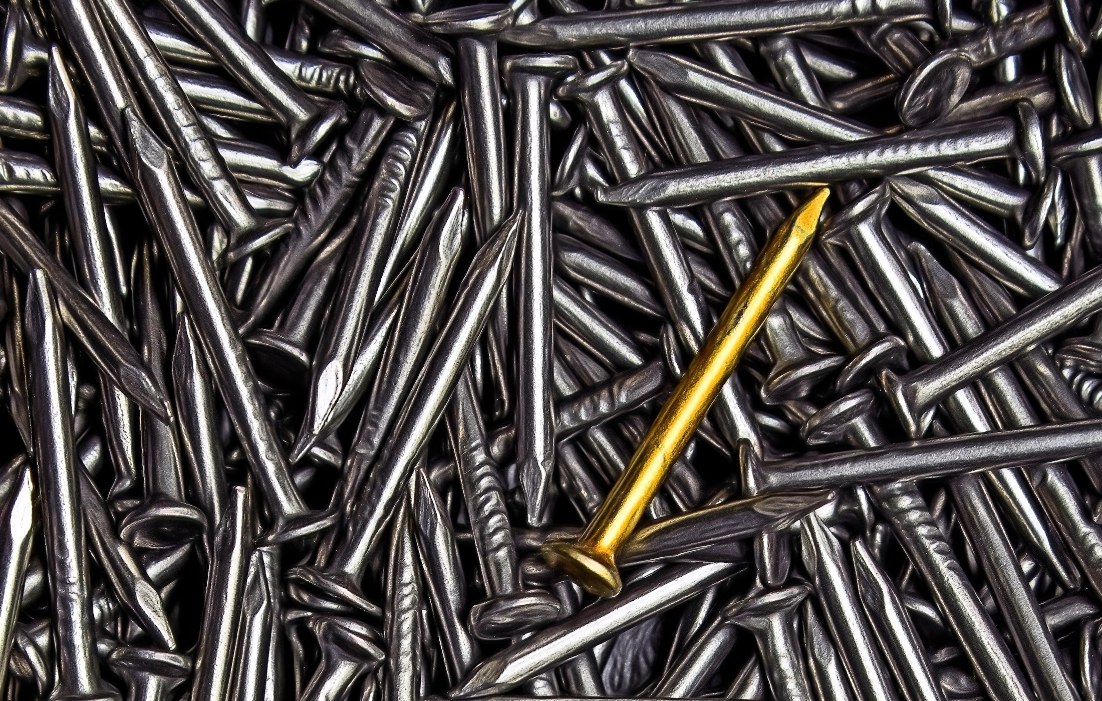 gold nail atop pile of silver nails